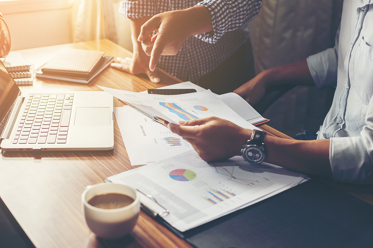 Businessmen's hands pointing at financial charts that display alternative and private investment strategies.